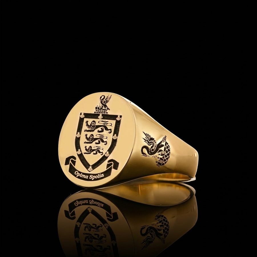 Gold signet ring engraved with a three-lion coat of arms and motto scroll, with a heraldic beast on the shoulder